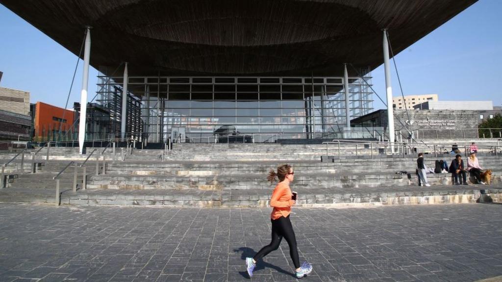 A woman jogging in front of the Senedd