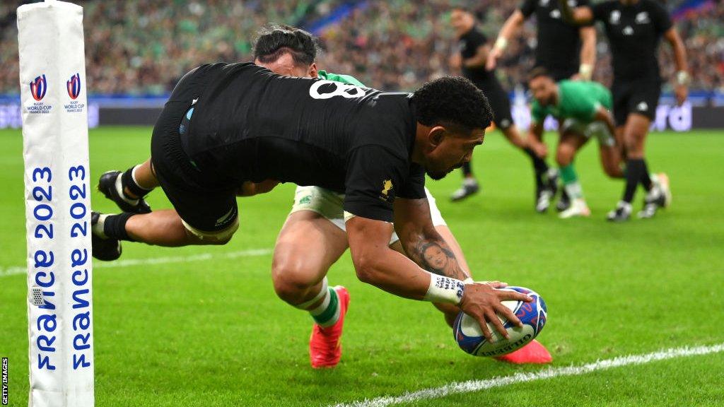 Ardie Savea dives over the line with a France 2023 branded corner flag in close attendance