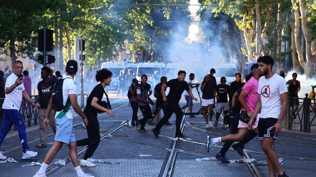 Protesters run from launched tear gas canisters during clashes with police in Marseille, southern France on 1 July 2023