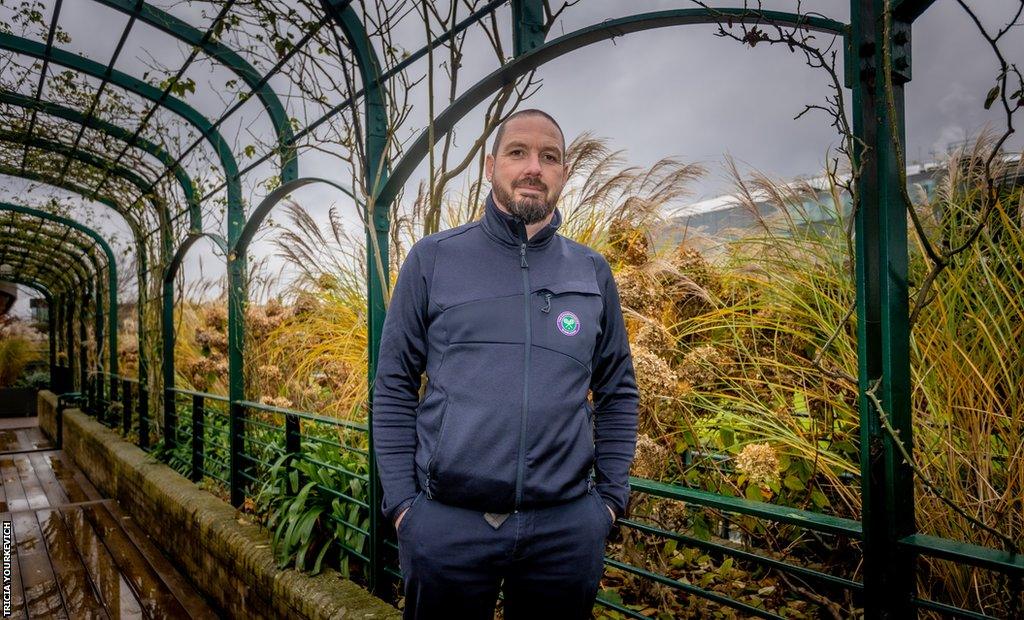 Portrait of Martyn Falconer standing under the rose arbour at Wimbledon