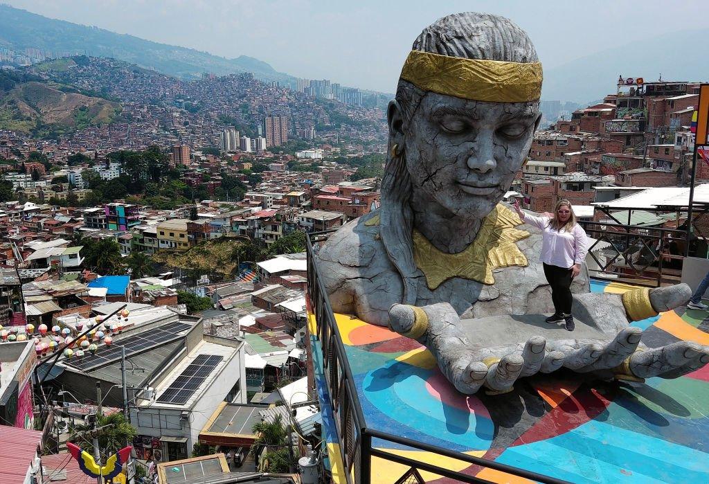 A tourist poses for a photo in the Pachamama sculpture by artist Jorge Jaramillo