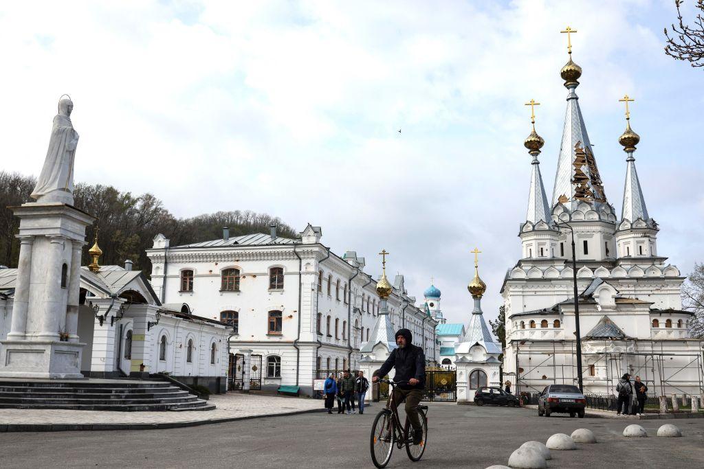 A man ride his bicycle near the damaged Sviatohirsk Cave Monastery, an Orthodox Christian monastery on the bank of the Seversky Donets River near the town of Sviatohirsk (Svyatohirsk)