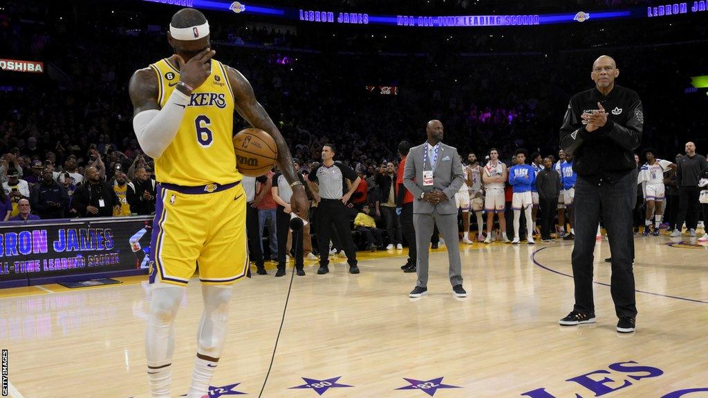 An emotional Lebron James covers his face as he makes a speech on court