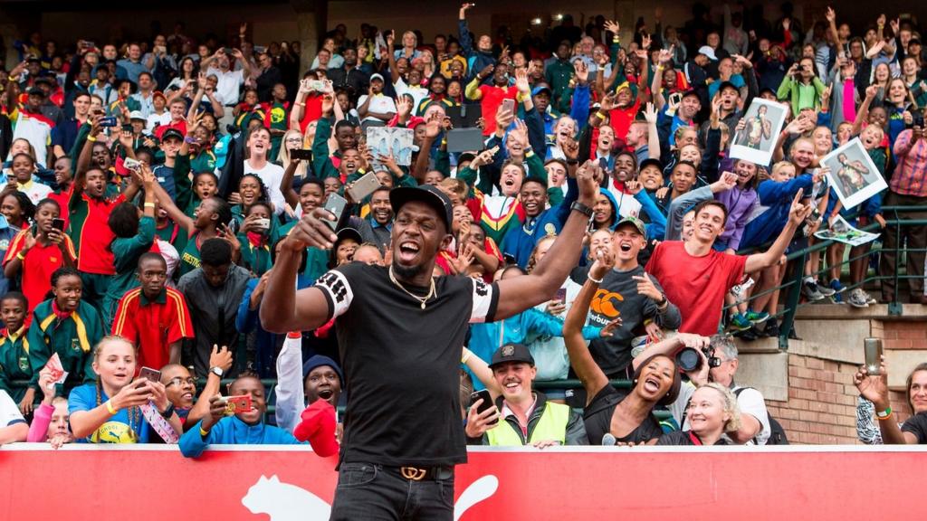 Retired Jamaican Olympic and World champion sprinter Usain Bolt poses for a selfie with spectators as he arrives for the PUMA School of Speed Athletic event at the Ruimsig Stadium in Roodepoort, Johannesburg, on January 29, 2018