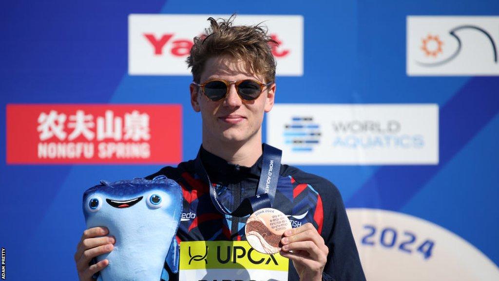 Hector Pardoe lifts his bronze medal on the podium