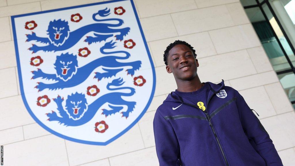 Kobbie Mainoo posing in front of an England badge