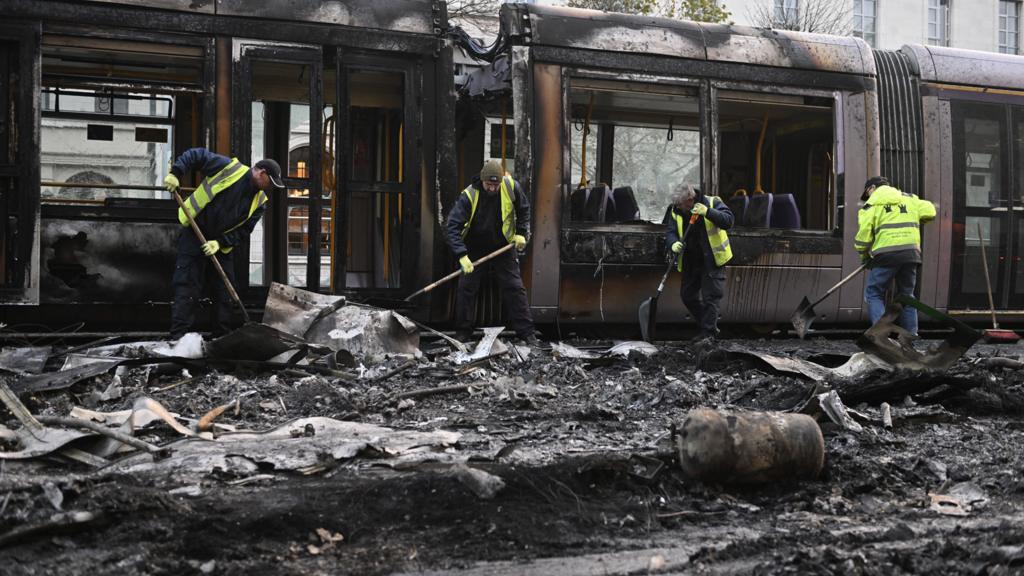 Workers clean up the debris of a burnt train in Dublin