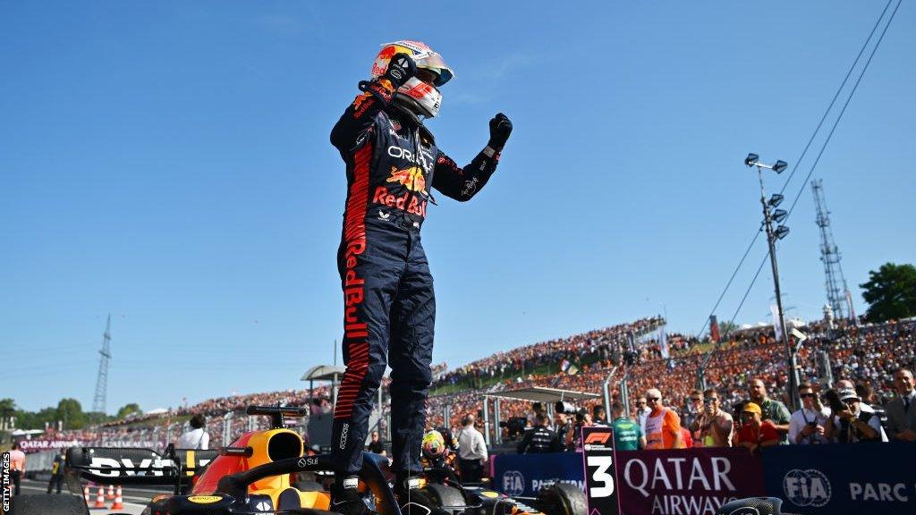 Max Verstappen stands on his Red Bull as he gets out of the car and celebrates winning the Hungarian Grand Prix