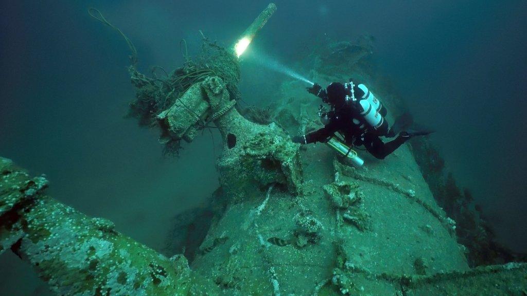 Diver Chris de Putron inspects the submarine's gun