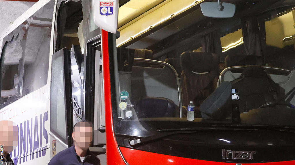 A close-up of the Lyon team coach shows damage to some of the windows