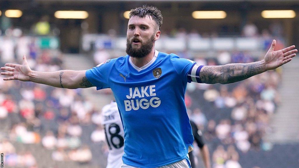 Notts County captain with his arms outstretched after scoring against MK Dons