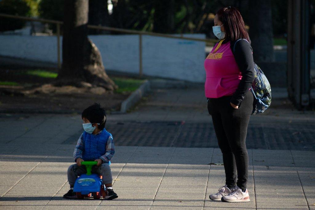 A boy in his toy car, and his mother, stroll through the streets of Santiago, on May 13, Santiago, Chile.