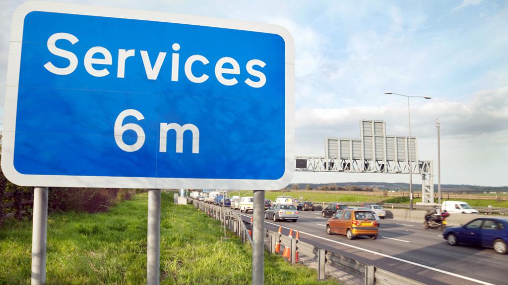 Motorway services sign next to a busy road