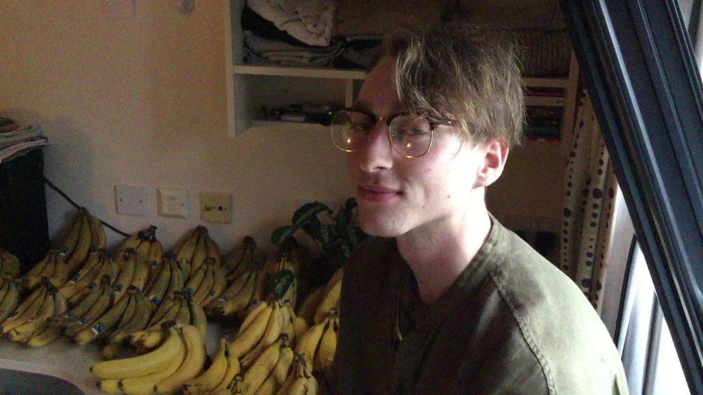 A man sat with hundreds of bananas