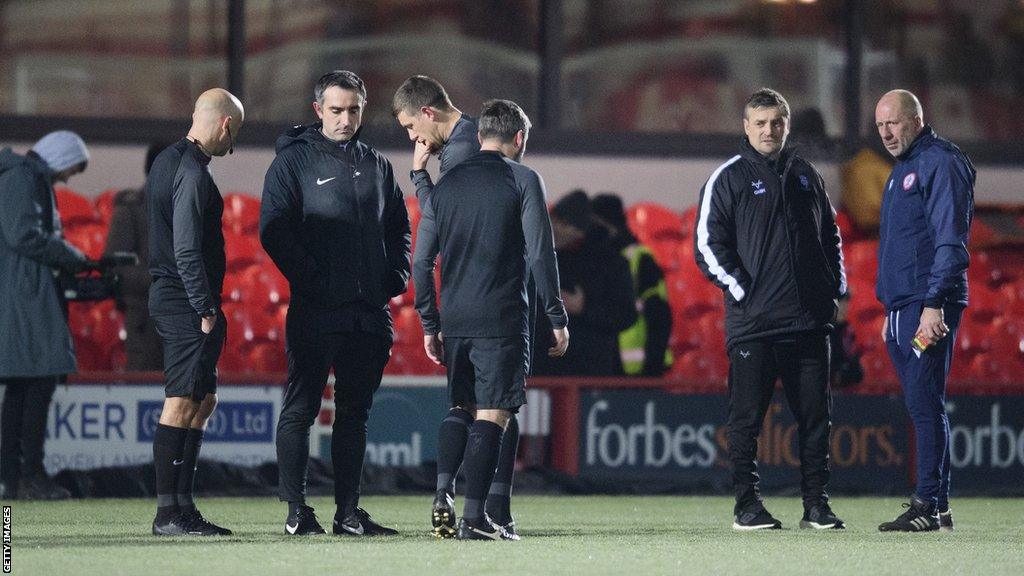 Referee Martin Woods and his assistants call the game off with Lincoln City head coach Michael Skubala and Accrington Stanley assistant manager Jimmy Bell