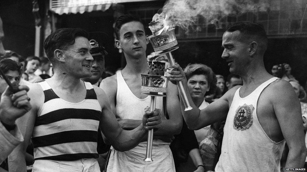 Two torch bearers pose for a photo with their Olympic torches.