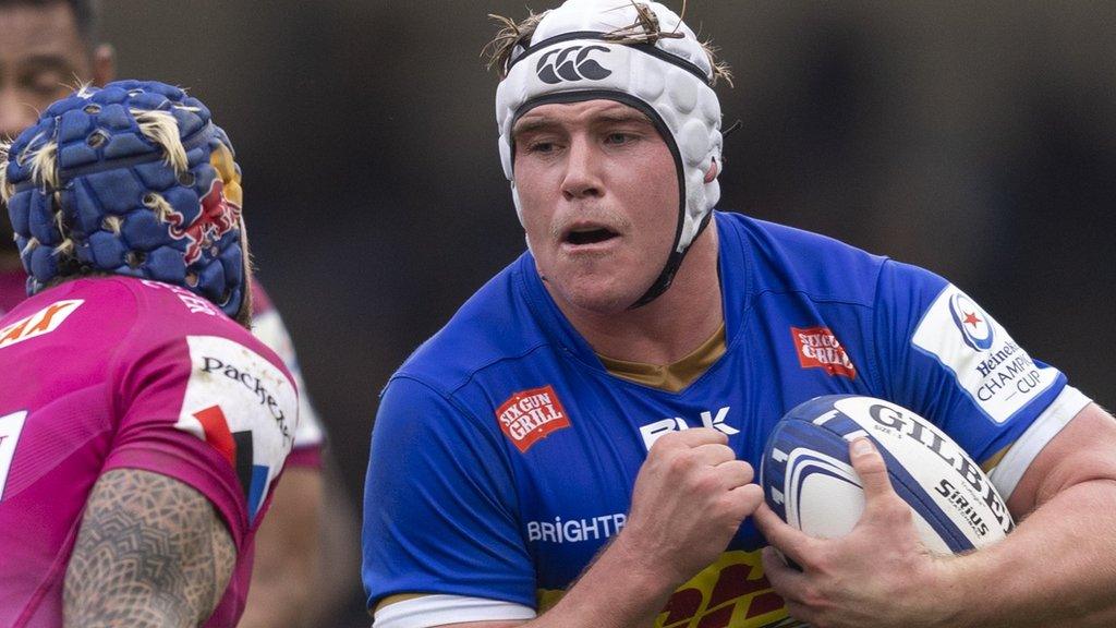 Ernst van Rhyn, with ball tucked under his arm, braces himself to barge past an Exeter Chiefs covering defender who is stooping to make a tackle