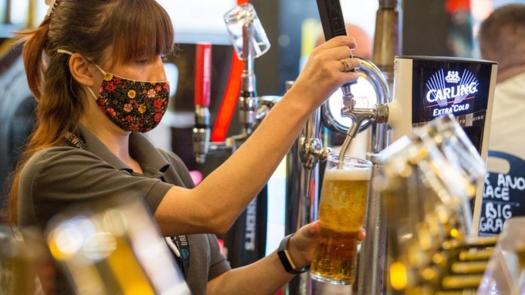 A woman serves a pint in a bar