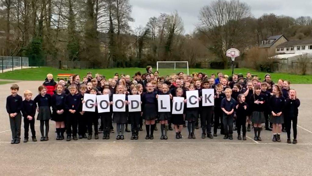 School children holding a 'good luck' sign in the school playground