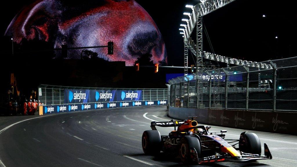 Max Verstappen drives round the circuit with the Sphere showing a solar style image in the background