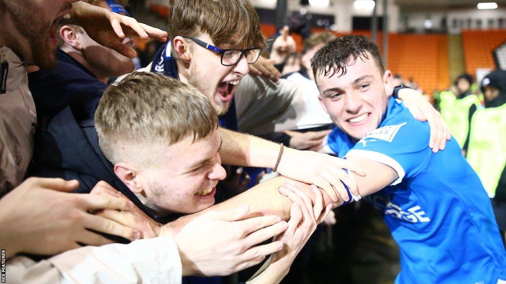 Harrison Burrows celebrates with fans as Peterborough clinch a place at Wembley in the EFL Trophy