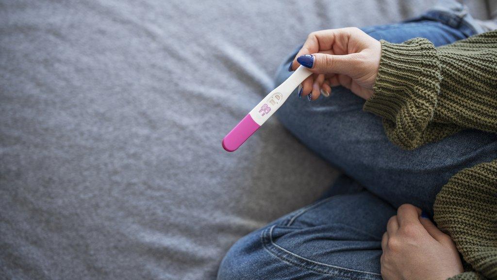 Unrecognisable woman holding positive pregnancy test.