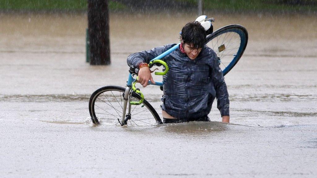 James Archiable carries his bike through the flooded intersection at Taylor and Usenet near downtown Houston, Texas, USA, 27 August 2017