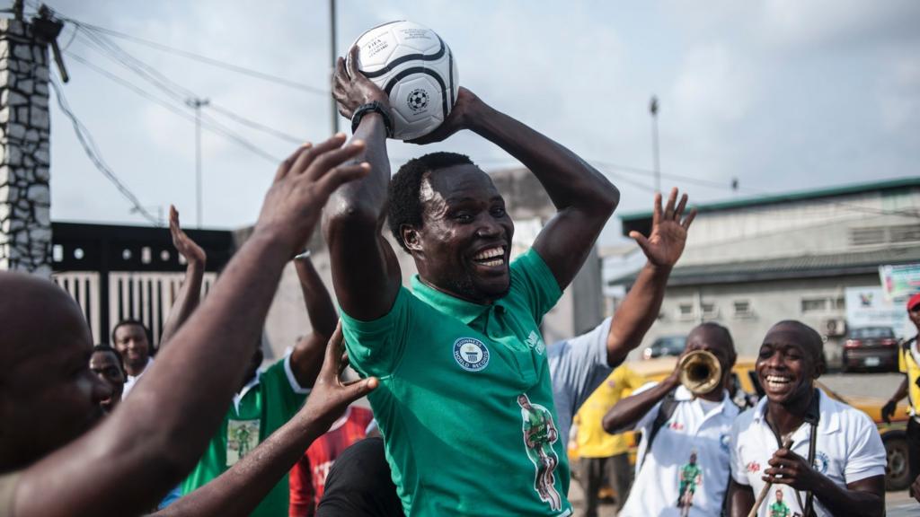 Harrison Chinedu celebrates after completing 103,6 km balancing a football on his head while riding a bicycle