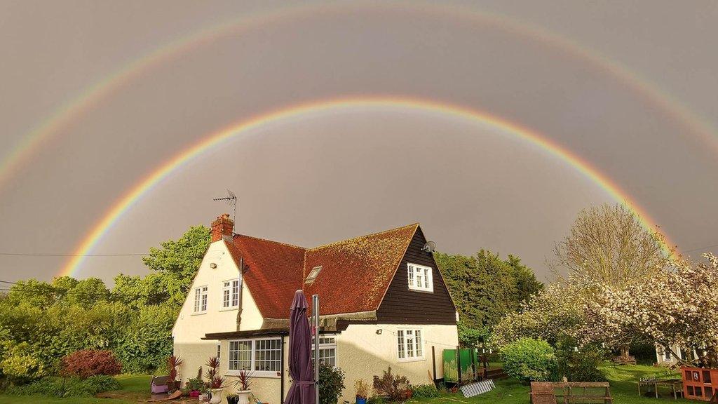 A double rainbow over a white cottage