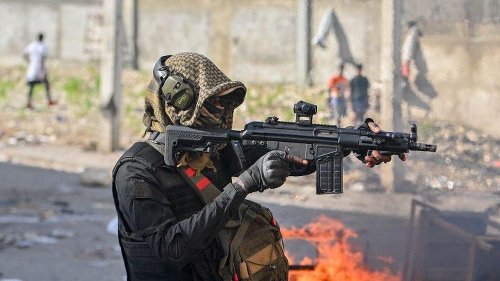 A police officer points a gun at protesters in Haiti, February 2024