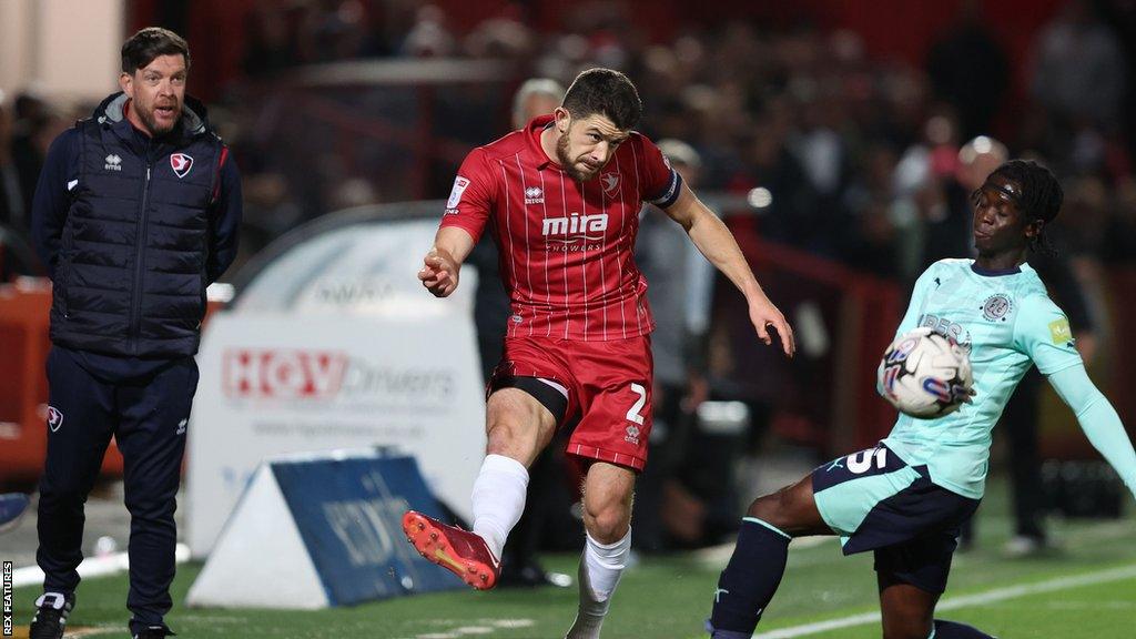 Darrell Clarke (left) watches from the touchline as Cheltenham's Sean Long challenges a Fleetwood player for the ball