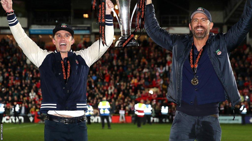 Rob McElhenney and Ryan Reynolds hold trophy aloft