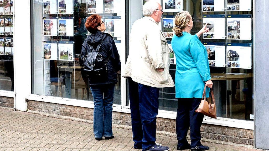 People looking in an estate agent's window