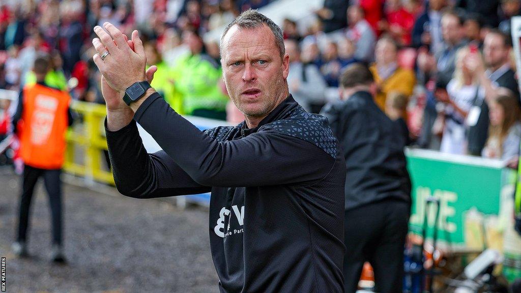 Swindon manager Michael Flynn applauds from the touchline during a game