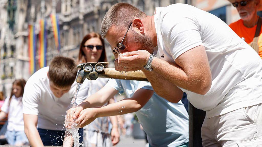 A man drinking from a water fountain in Munich