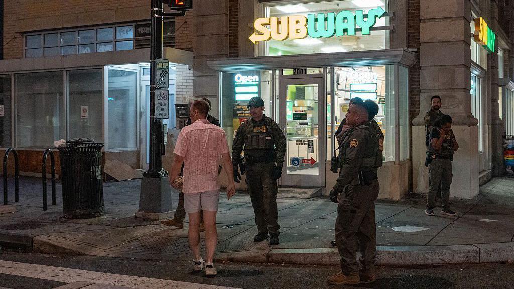 A man, who was later arrested for assaulting law enforcement with a sandwich, interacts with Border Patrol and FBI agents along the U Street corridor on 10 August.