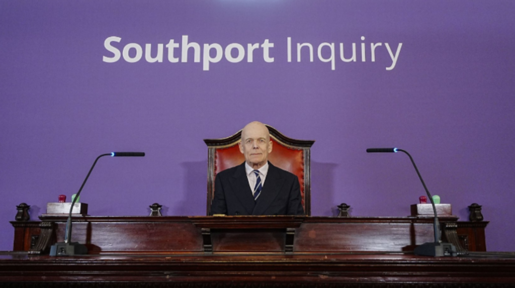 The Southport inquiry chairman sitting in front of a large Southport inquiry logo