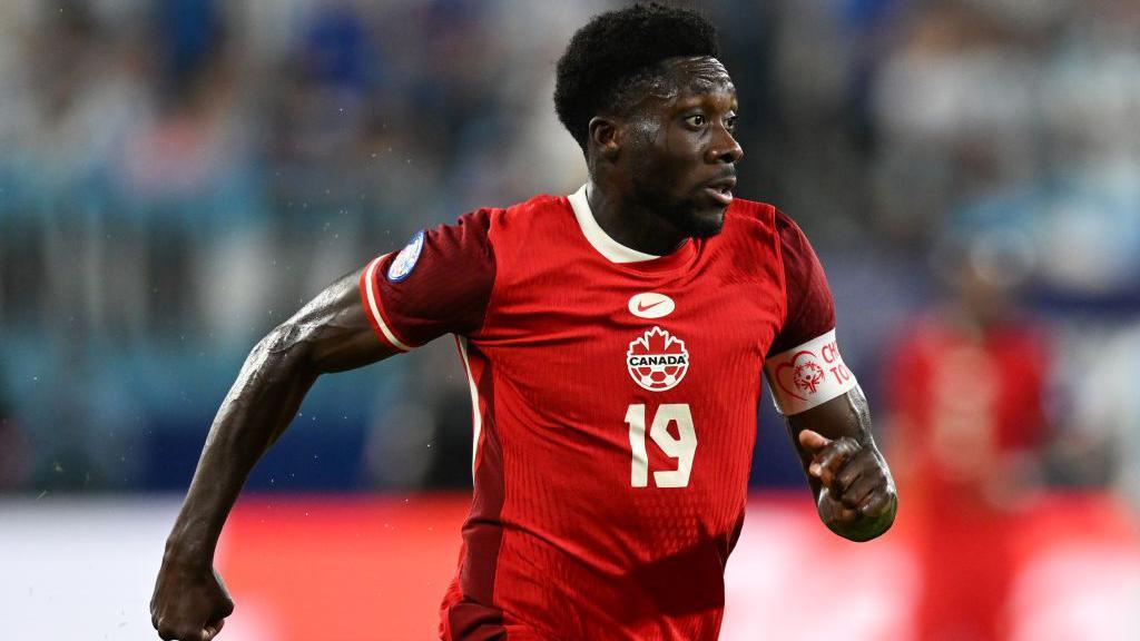 Alphonso Davies running in a red Canada top