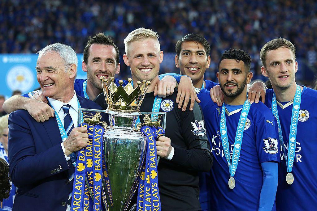 Leicester City manager Claudio Ranieri (far left) holds the Premier League trophy with goalkeeper Kasper Schmeichel (third left) with team-mates around them