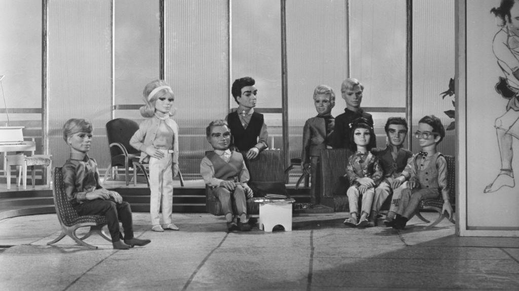 A black and white image of the original Thunderbirds, with nine of the puppets standing on the set.