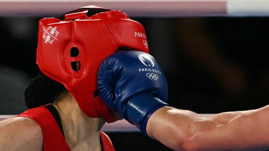 A boxing glove lands on the face of a fighter