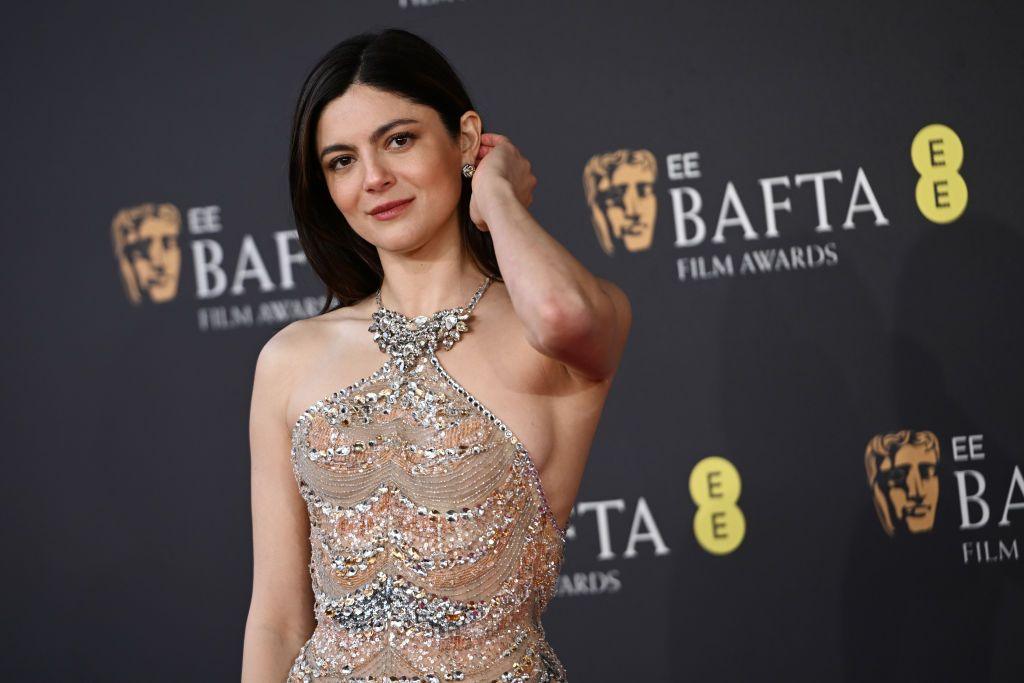 Monica Barbaro in a fitted, sparkling gown in pale colours with jewels encrusted into the fabric