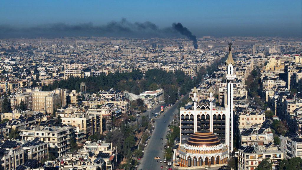 A birds-eye picture of Aleppo with black smoke rising above the city. 