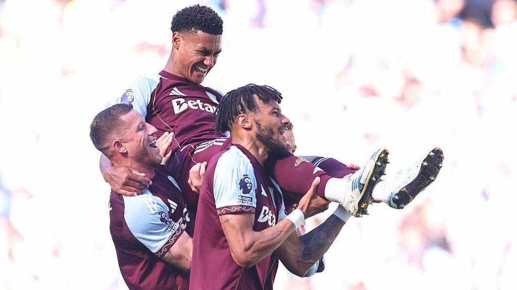 Ollie Watkins smiles as he is held aloft by Ross Barkley and Tyrone Mings