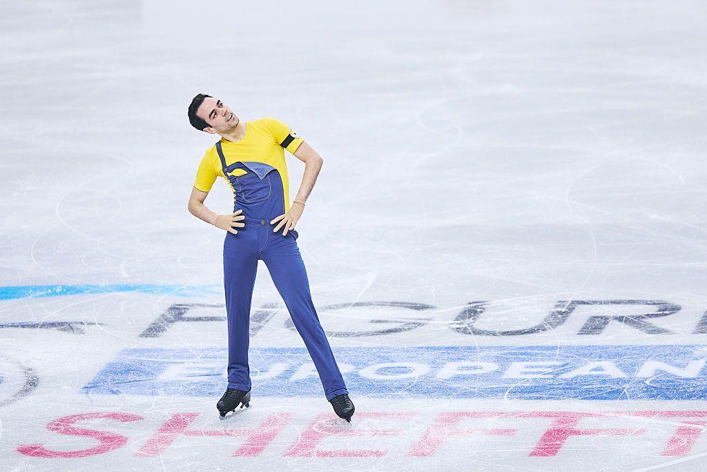 Tomas-Llorenc Guarino Sabate of Spain competes in figure skating wearing his yellow top and blue dungarees. 