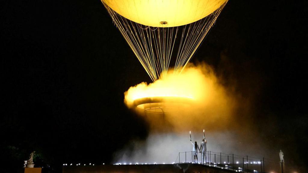 The two final Olympic torchbearers watch as the Olympic cauldron is lifted into the air on a giant balloon