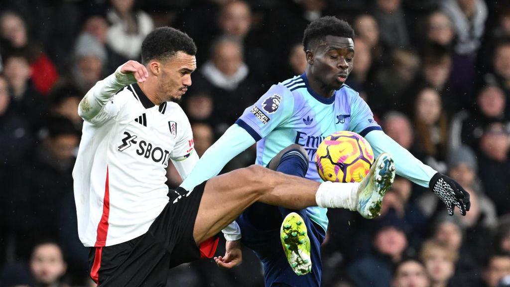 Bukayo Saka battles for the ball