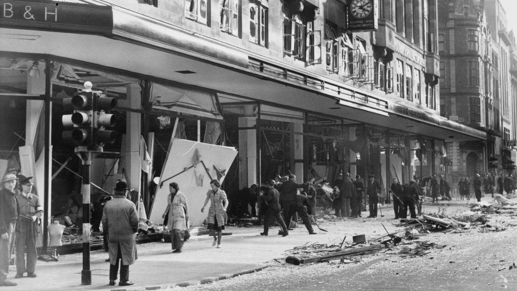 Shop assistants and ARP staff clear debris from damaged windows at Bourne & Hollingsworth's department store in London's West End after a German bombing raid in 1940