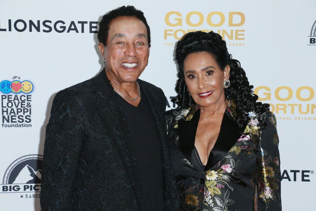 Smokey Robinson smiles and poses for the camera with his wife, Frances, on the red carpet of a film premiere.