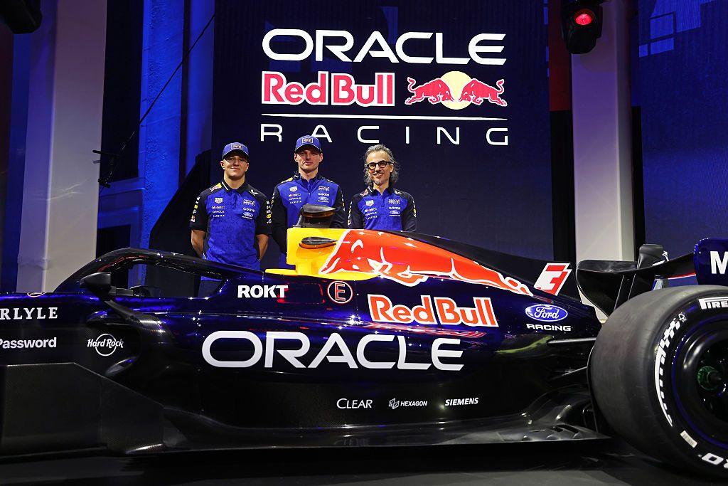 Isack Hadjar, Max Verstappen and team principal Laurent Mekies stand behind the new Red Bull car during the Red Bull Racing season launch at Michigan Central Station